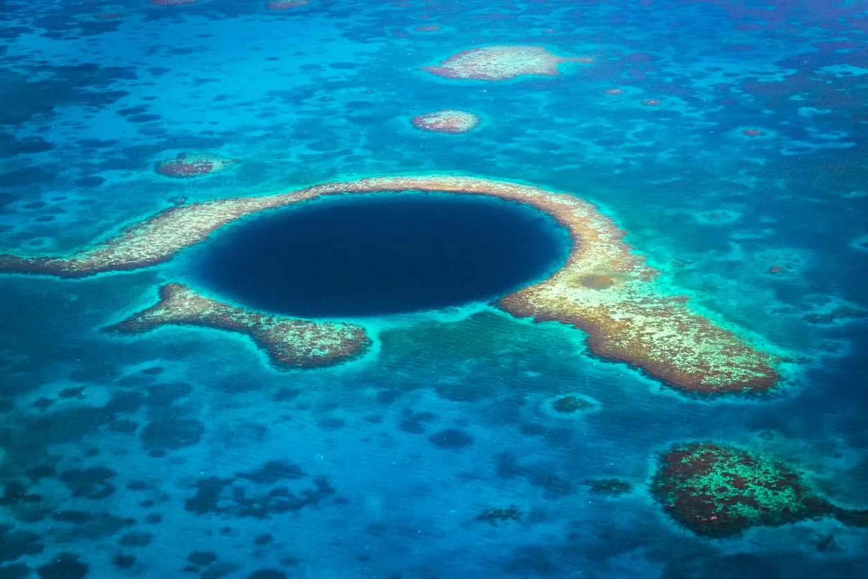 Vue aérienne du célèbre site de plongée Blue Hole dans le récif Lighthouse, à l'est de l'atoll de Turneffe dans la mer des Caraïbes, au Belize, en Amérique centrale. © iStock / Mlenny